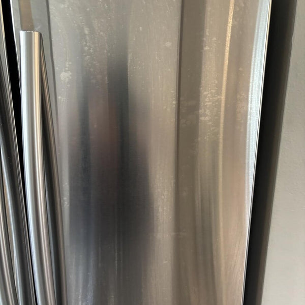 Porte de frigo en inox avec des marques et des traînées